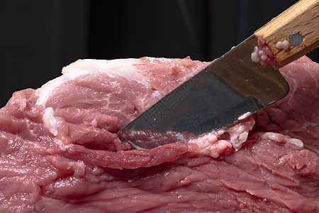 在特写镜头中用刀将猪肉或牛肉切成薄片 肉类菜肴和食品的准备 烤羊肉串 烧烤或烤肉串用的红肉片 用刀切生鲜肉 食谱餐厅厨房木板营养图片