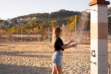 一个穿短裤的女孩 和一件黑色T恤 在海滩附近的淋浴棕榈假期热带女士海洋排球异国皮肤身体享受图片