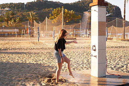 一个穿短裤的女孩 和一件黑色T恤 在海滩附近的淋浴金发女郎排球女士享受旅行假期海洋棕榈皮肤乐趣图片