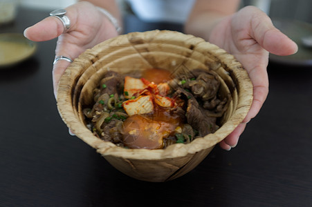 妇女手与日本的九东 鸡蛋或日本牛肉碗 鸡蛋在有机木叶碗中图片