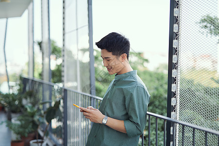 年轻人站在阳台上 在手机上发短信商业电话成人金融男人呼唤消息咖啡图片