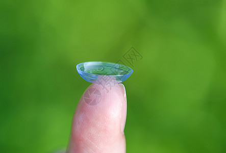 在绿色夏季自然背景模糊的指尖上用透明隐形透视镜光学镜片白色宏观保健眼睛验光师眼镜手指皮肤图片