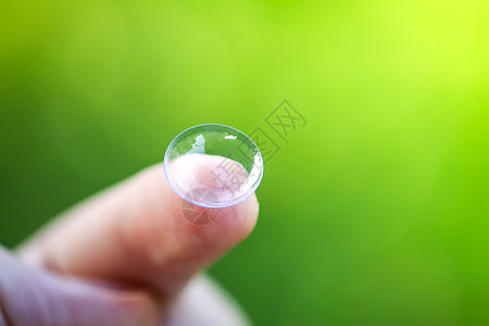在绿色夏季自然背景模糊的指尖上用透明隐形透视镜镜片光学眼镜卫生近视角膜验光师皮肤配镜师手指图片
