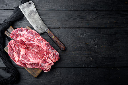 Ribeye 牛排 配有调味料和旧的屠宰刀 黑木桌底黑色木制餐桌背景 顶端视图平面 复制文字空间图片