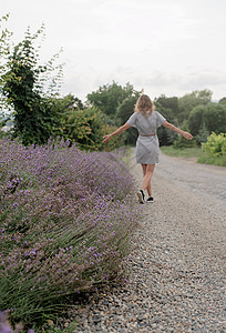妇女走在紫衣草田边旅行紫色农村农场国家蓝色小路女士园艺农业图片