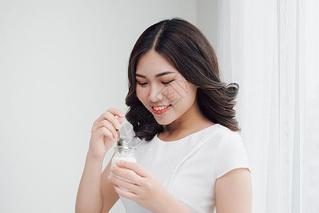 家里吃酸奶的年轻亚洲女人的肖像早餐微笑营养奶油女孩女性甜点勺子食物饮食图片
