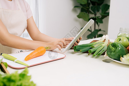 在厨房里用数字板片子的女人白色烹饪药片营养绿色饮食果汁男人食物排毒图片