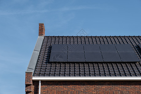 在阳光明媚的天空下 屋顶上附有太阳能电池板的新建房屋特写带有黑色太阳能电池板的新建筑 翻译 太阳能电池板 太阳能活力太阳能板晴天图片