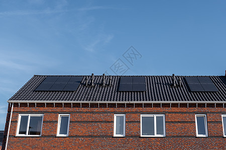 在阳光明媚的天空下 屋顶上附有太阳能电池板的新建房屋特写带有黑色太阳能电池板的新建筑 翻译 太阳能电池板 太阳能绿色控制板晴天力图片