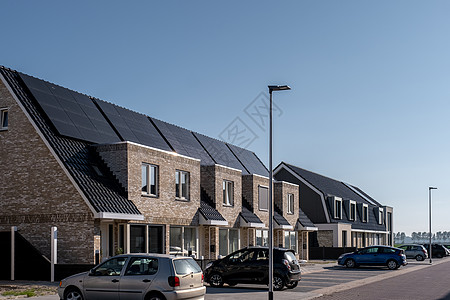 在阳光明媚的天空下 屋顶上附有太阳能电池板的新建房屋特写带有黑色太阳能电池板的新建筑 翻译 太阳能电池板 太阳能控制板电气光伏城图片
