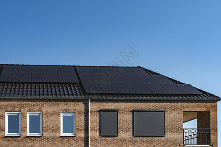 在阳光明媚的天空下 屋顶上附有太阳能电池板的新建房屋特写带有黑色太阳能电池板的新建筑 翻译 太阳能电池板 太阳能住宅房子发电机能图片