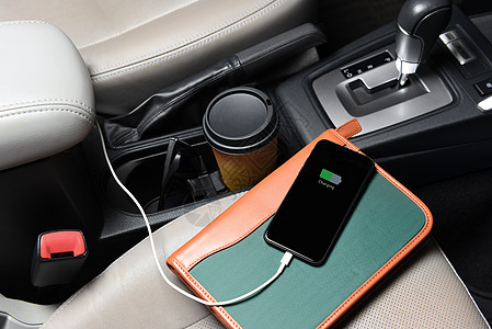 客座上有一部商务人士手机 用咖啡杯和笔记本插在汽车充电端口的汽车上图片