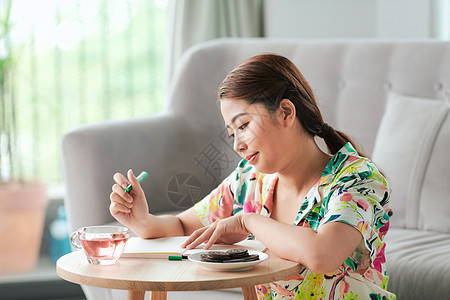 快乐笑笑的亚洲女人 日记坐在家里的地板上背景图片