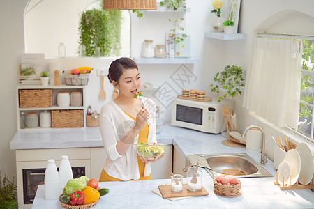 美丽的笑脸女人在现代厨房里吃新鲜有机蔬菜沙拉餐饮快乐成人微笑素食主义者胡椒饮食桌子女士食物图片