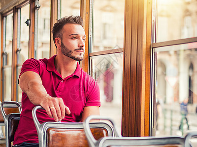 英俊的年轻人骑在城里的电车或旧巴士上孤独窗户民众生活座位公共汽车骑术工作乘客城市图片