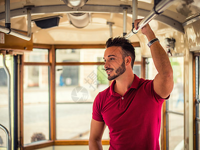 英俊的年轻人骑在城里的电车或旧巴士上民众男人孤独生活窗户火车工作通勤者骑术公共汽车图片