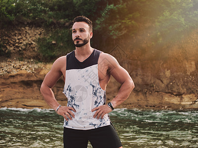在河边站立的健壮运动青年男子旅行肌肉远足乐趣衬衫背心岩石身体山脉远足者图片