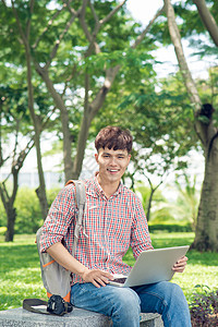 使用笔记本电脑坐在公园的亚洲学生图片