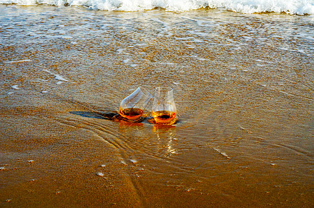 海浪冲洗的沙子上 一杯口味饮料 在海滩上放松一阵风光闲暇运动泡沫活力烈酒蓝色沙滩麦芽海岸线天气图片