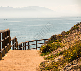 沿着海岸的木制长廊位于 Andalucja 的悬崖岩石上栏杆木头天空石头溶胶人行道灌木丛海滩小路海洋图片
