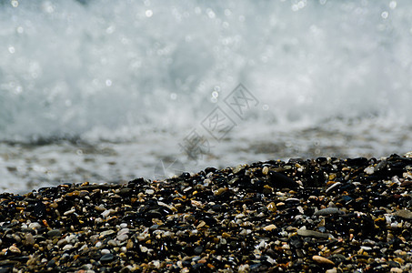 被海浪冲刷的卵石滩小而各种石头形成了海岸波浪蓝色卵石鹅卵石小路砂砾海洋地面岩石支撑图片