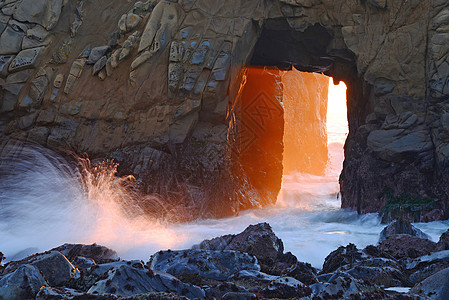 穿透洞的光线海浪海景海滩岩石阳光悬崖海岸日落背景图片
