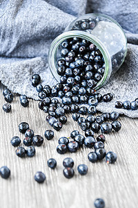 有选择性的焦点 新鲜蓝莓 从玻璃罐里溢出 在木质背景上 果汁丰盛的野生森林浆果营养覆盆子饮食桌子乡村食物水果收成花园静物图片