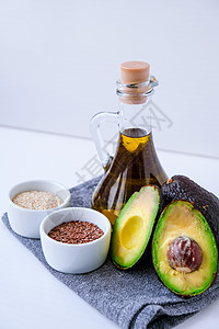在玻璃瓶中的橄榄油与芝麻和亚麻籽 新鲜成熟的哈斯鳄梨 健康饮食 素食成分 纯素饮食 生酮饮食图片