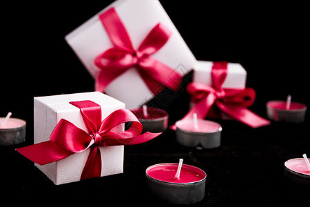 黑色背景的粉红丝带和蜡烛礼品火焰烛台黑暗蓝色问候语盒子紫色丝带奢华婚姻图片