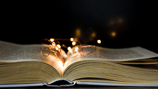 打开书 在黑色背景上点亮它 旧书 在黑色背景上用魔法灯打开魔法书图片