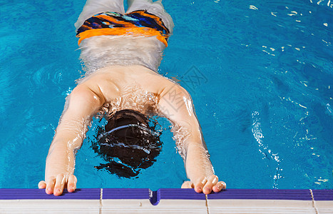 青少年游泳学游泳时在室内游泳池游泳的少年男孩背景