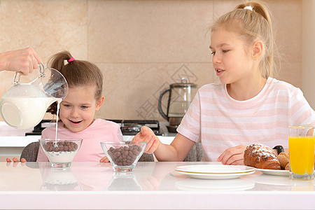 母亲在厨房的桌子上为两个女儿提供早餐 这是幸福的单身母亲概念单亲成人女士儿子家庭女孩女性青少年男生牛奶图片