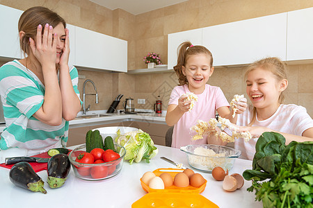 母亲和两个女儿在厨房做饭 享受快乐 幸福的家庭和单身母亲的概念婴儿乐趣朋友们烹饪喜悦烘烤姐姐女孩食物面粉图片
