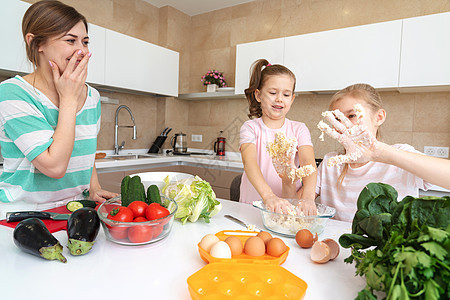 母亲和两个女儿在厨房做饭 享受快乐 幸福的家庭和单身母亲的概念友谊烹饪微笑面粉桌子姐姐别针婴儿团队童年图片