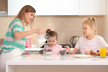 母亲在厨房的桌子上为两个女儿提供早餐 这是幸福的单身母亲概念男生面包女士女性投标成人童年妈妈青少年食物图片