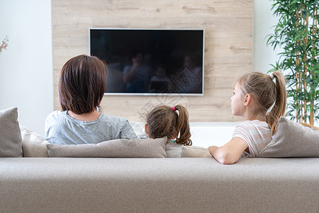 两个可爱的女儿在家看电视 幸福的家庭在教练身上放松了一下 很快乐的家图片