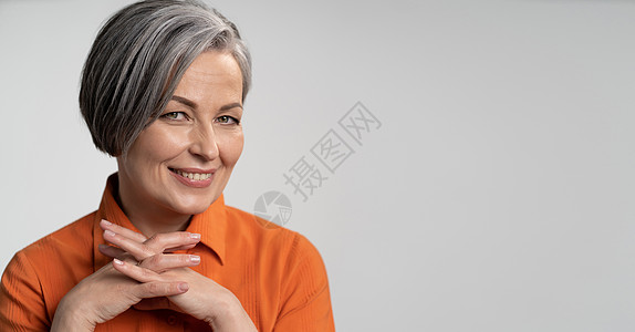 幸福的老年妇女微笑着手指交叉 身穿橙色衬衫 头部和肩部肖像的鲍勃发型女士 智慧的概念 右侧有复制空间的水平空白或模板图片