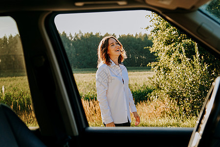 一个穿着白衬衫的年轻美女 正在城外休息着呢旅行白色座位女性头发假期商业机械快乐汽车图片