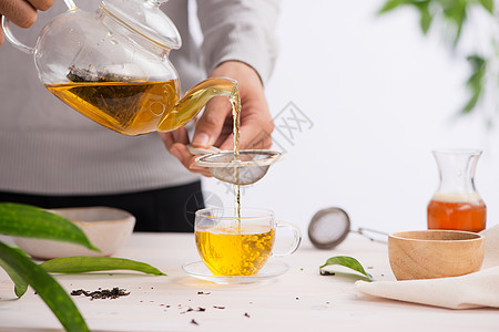 从一个茶壶的茶杯上 倒在木制桌子上的茶杯里棕色玻璃杯子黑色饮料白色食物黄色绿色英语图片