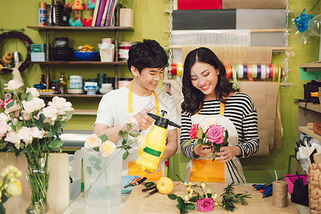 花店家用木制背景在桌边做花束植物零售职业成人商业微笑女孩女性夫妻店铺图片