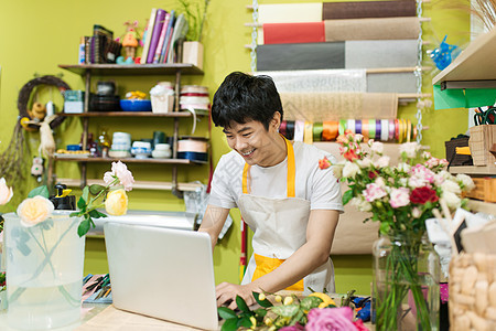 在花店柜台使用笔记本电脑的 快乐的亚洲男性花卉师药片店铺花艺技术零售顾客微笑服务男人职业图片