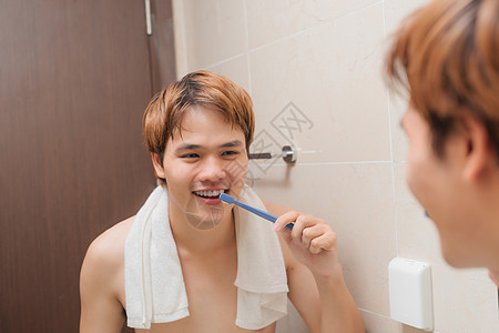 帅哥早上在洗手间刷牙的英俊男人卫生浴室牙齿口服牙科牙刷反射镜子图片