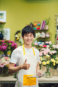 微笑的男花匠在花店拿着剪贴板的肖像图片