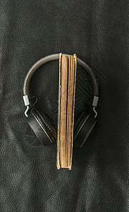 以黑皮革背景覆盖耳机的旧书剪贴版大学文学教科书桌子音乐教育学习空白知识教学图片