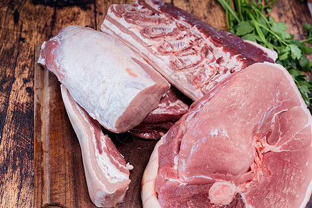 木板上许多新鲜的猪肉块 在木制切割板上腰部香菜牛扒食物鱼片腹部牛肉红色美食屠夫图片