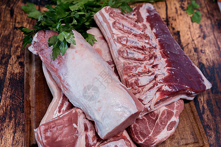 木板上许多新鲜的猪肉块 在木制切割板上牛扒腹部白色木头烹饪猪肉鱼片牛肉屠夫美食图片