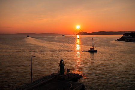 在亚得里亚海及其在克罗地亚斯普利特港入口处倒影中玩耍的船只上日落海岸港口全景景观旅游地标天线城市运输游艇图片