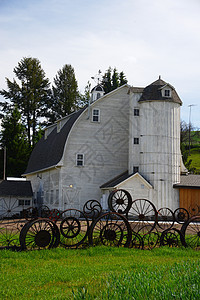 一个带轮子栅栏的谷仓黄色工匠农村绿色风景白色农业车轮农场建筑图片