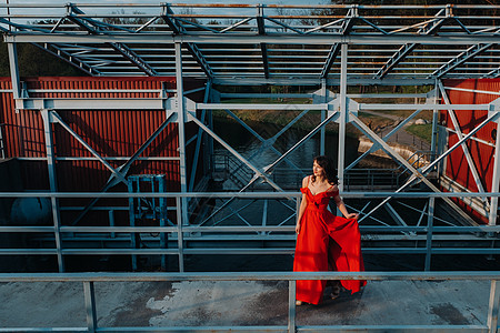 日落时 一个女孩在靠近河流的水坝上穿着红色礼服跑步魔法节日裙子女性成人太阳女孩摄影女王图片