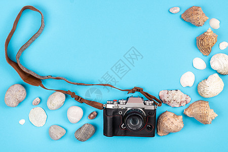 蓝色背景上的相机和贝壳 旅行的背景夏令石头框架海滩配件假期海洋绳索游客说谎图片